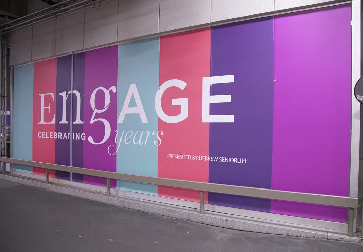 Large multicolored billboard sign with word ENGAGE in large letters