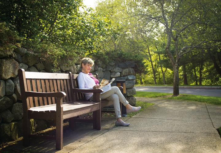 A female Orchard Cove resident sits on a bench and reads