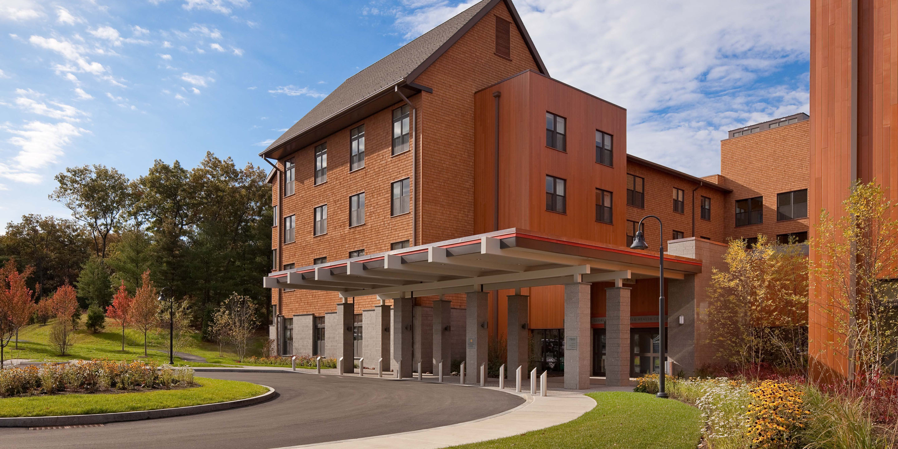 A curved entrance road winds through fall foliage to the Health Care Center at NewBridge on the Charles, home to Hebrew Rehabilitation Center in Dedham.