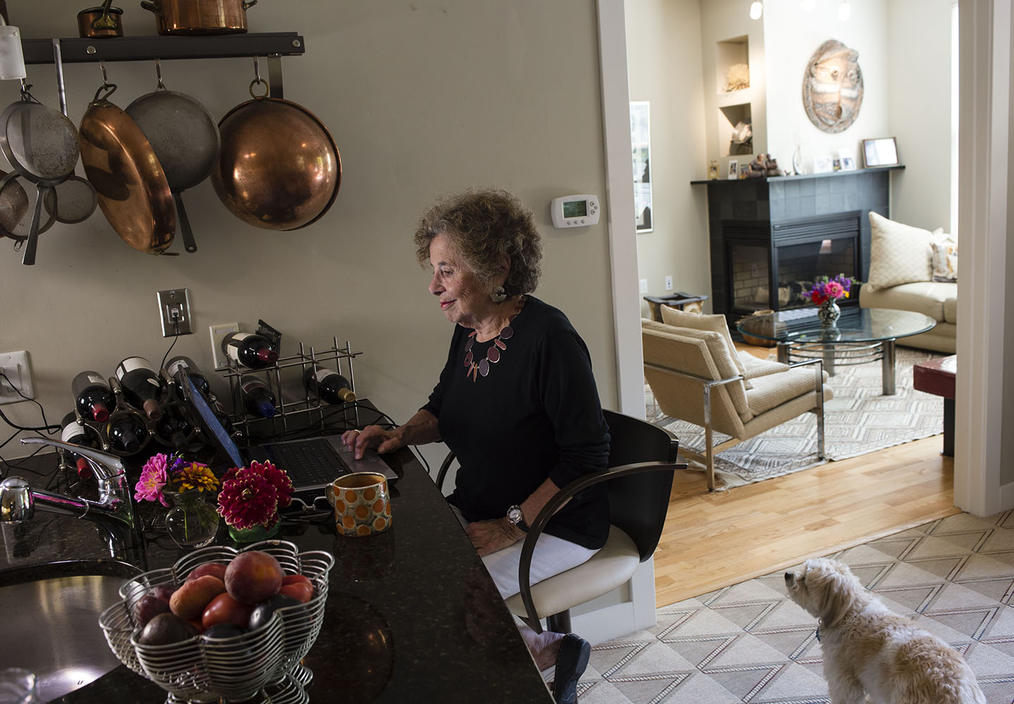 Woman in kitchen with copper pans and threshold into living room.