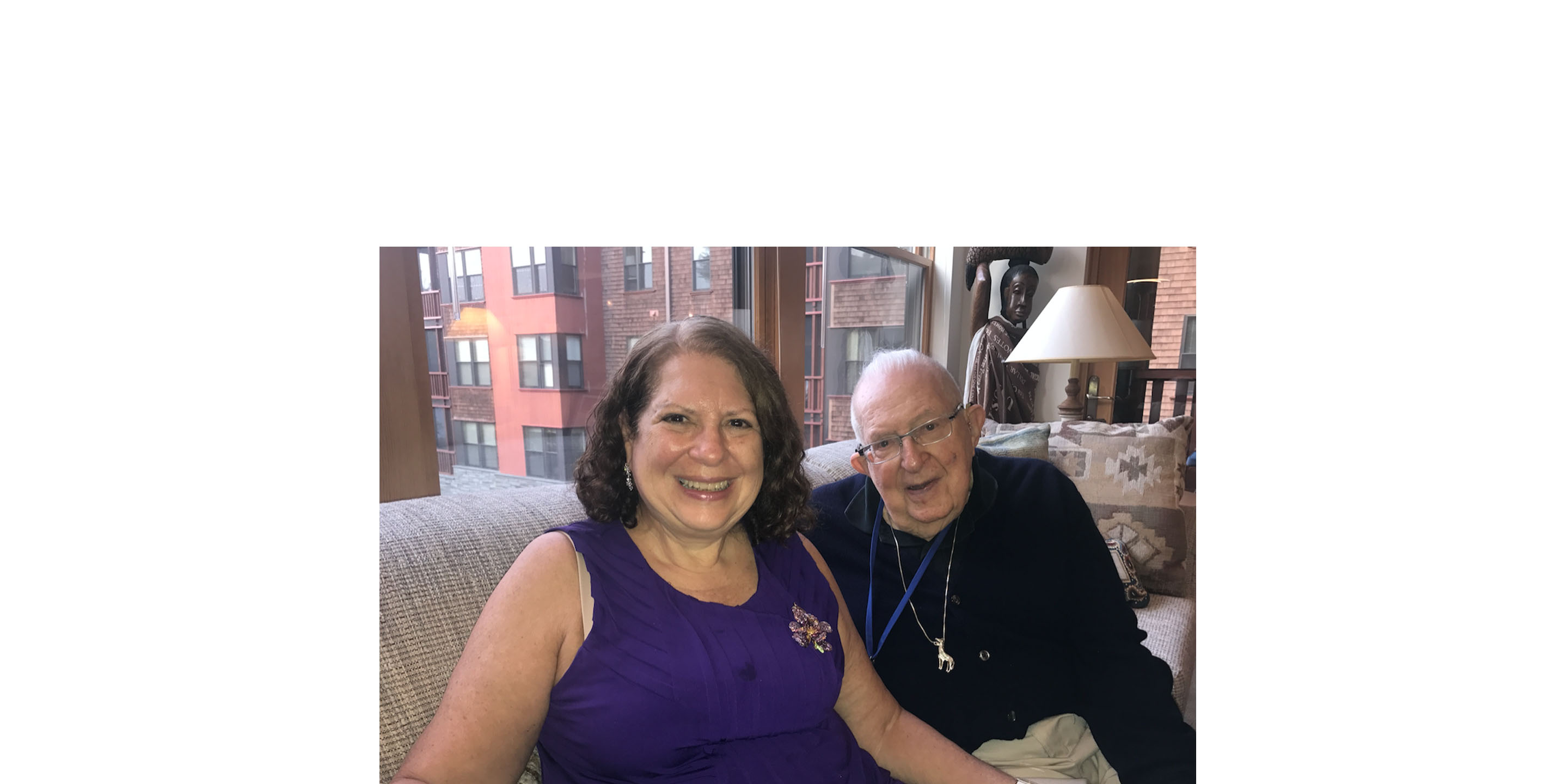 A daughter sits with her senior father in his NewBridge apartment.