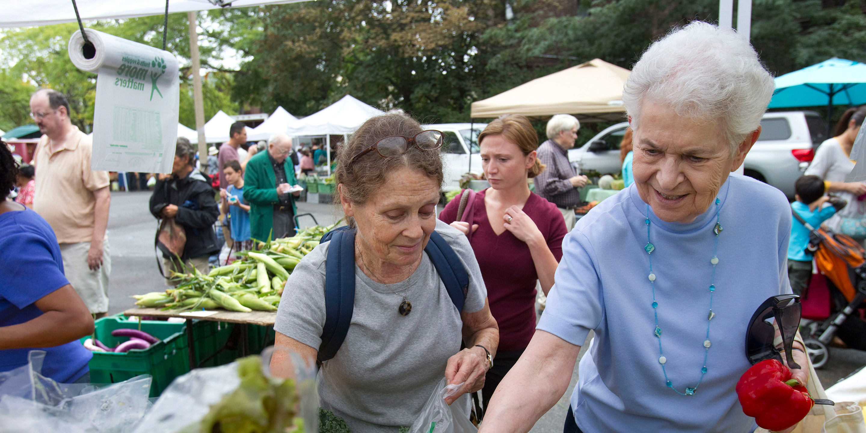 Two women pick out vegetables at a Farmer's Market 