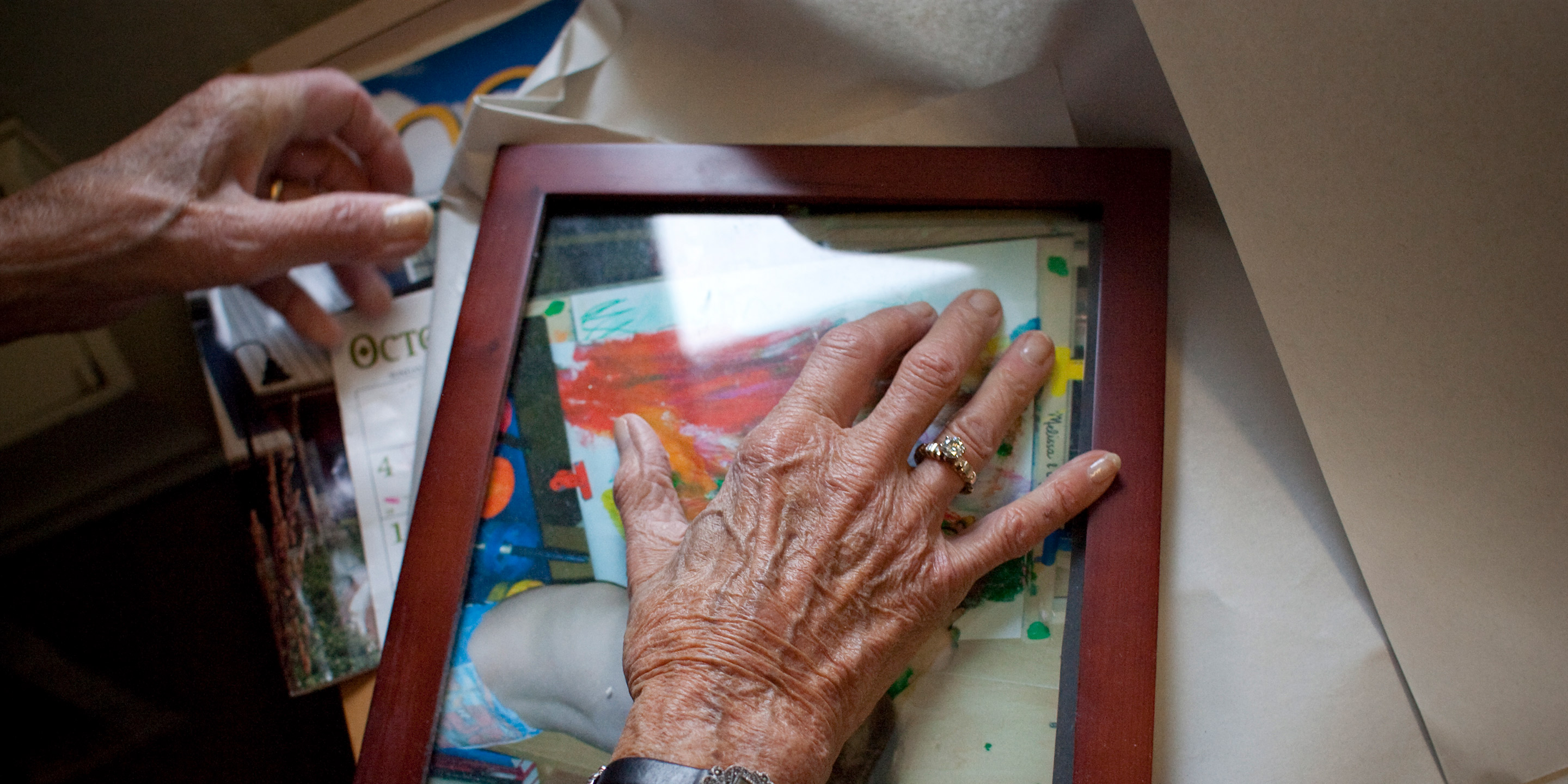 A woman wearing a ring places her hand over a picture frame 