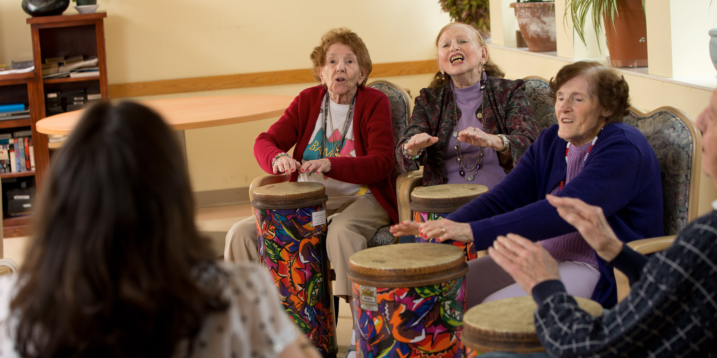 Residents at Hebrew SeniorLife participate in a music therapy activity involving drums