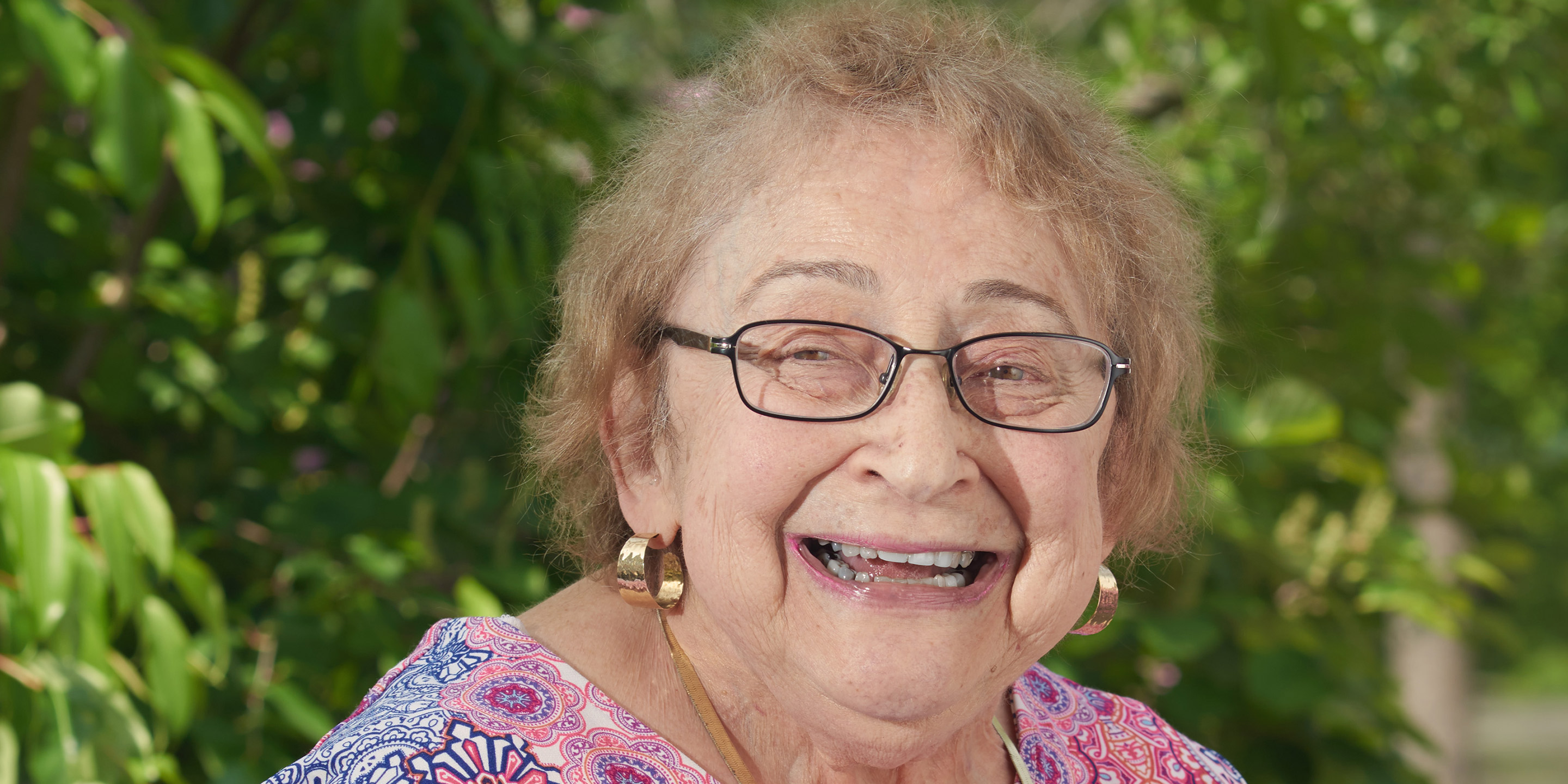 A female smiles while sitting outside 