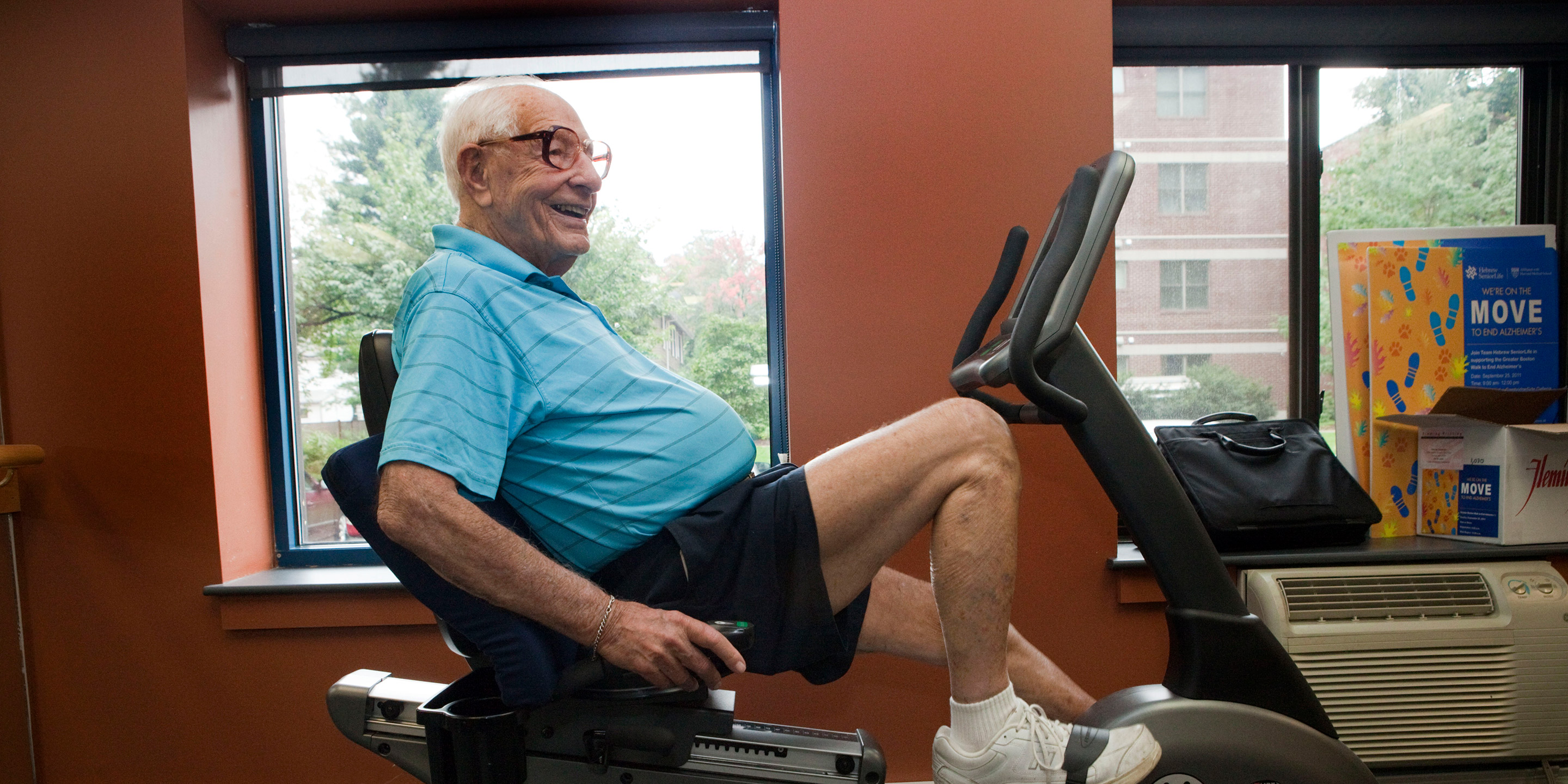 Male resident smiles while working out on a stationary bicycle in a gym 