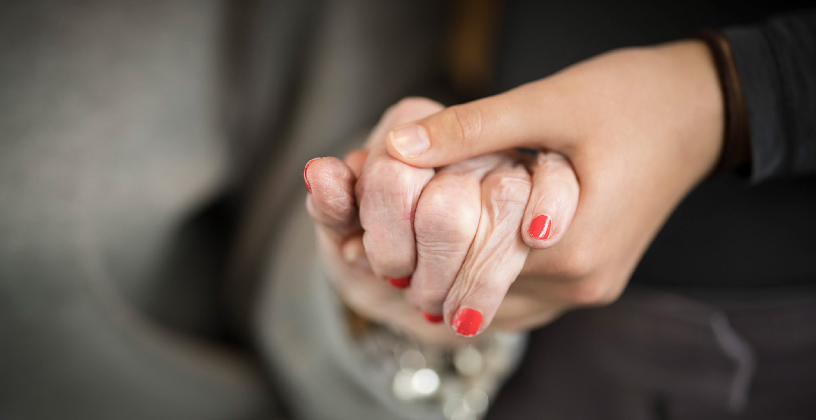 Two people hold hands - one of them is wearing red nail polish