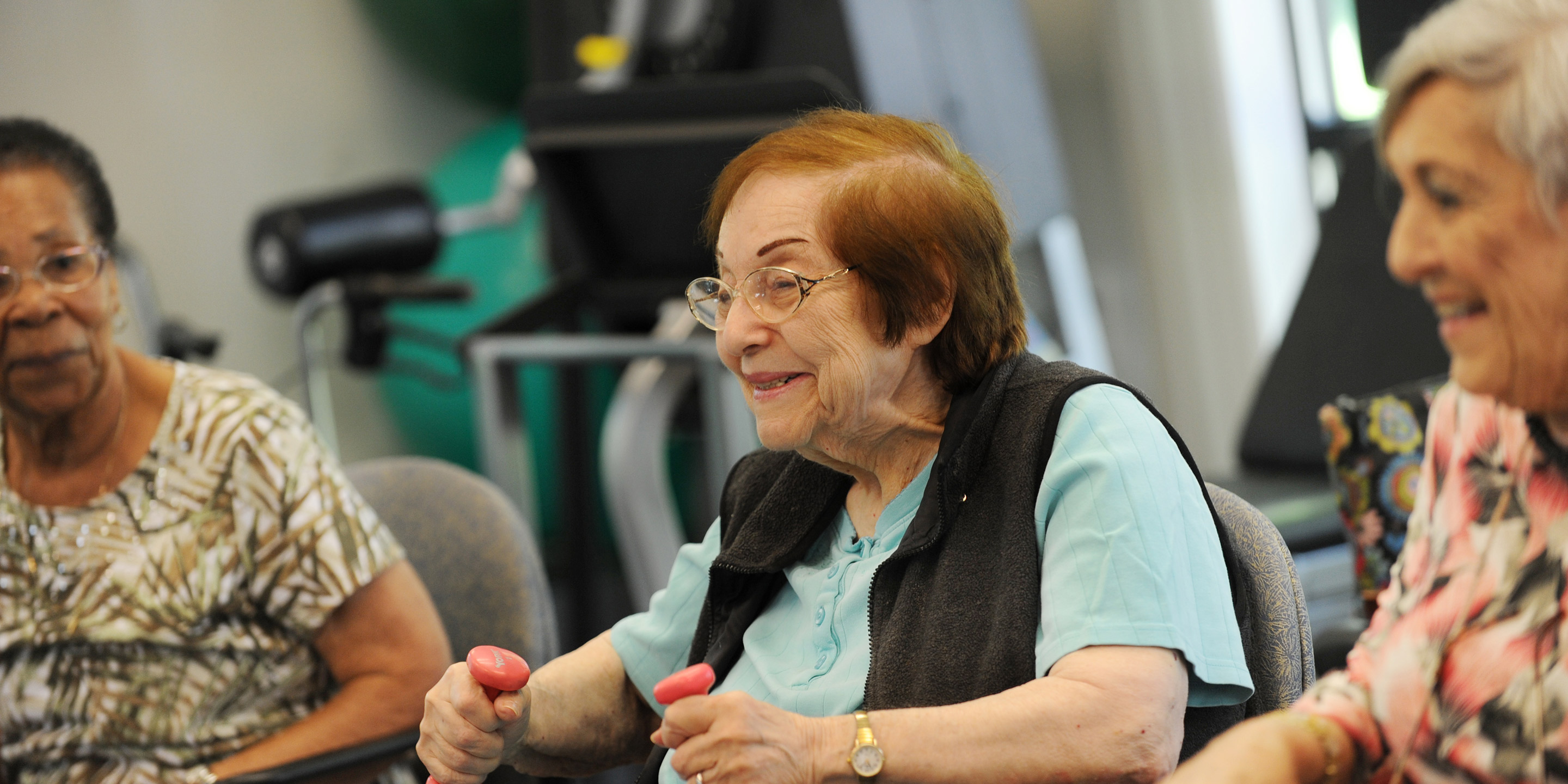 Three residents participate in a fitness class that involves weights