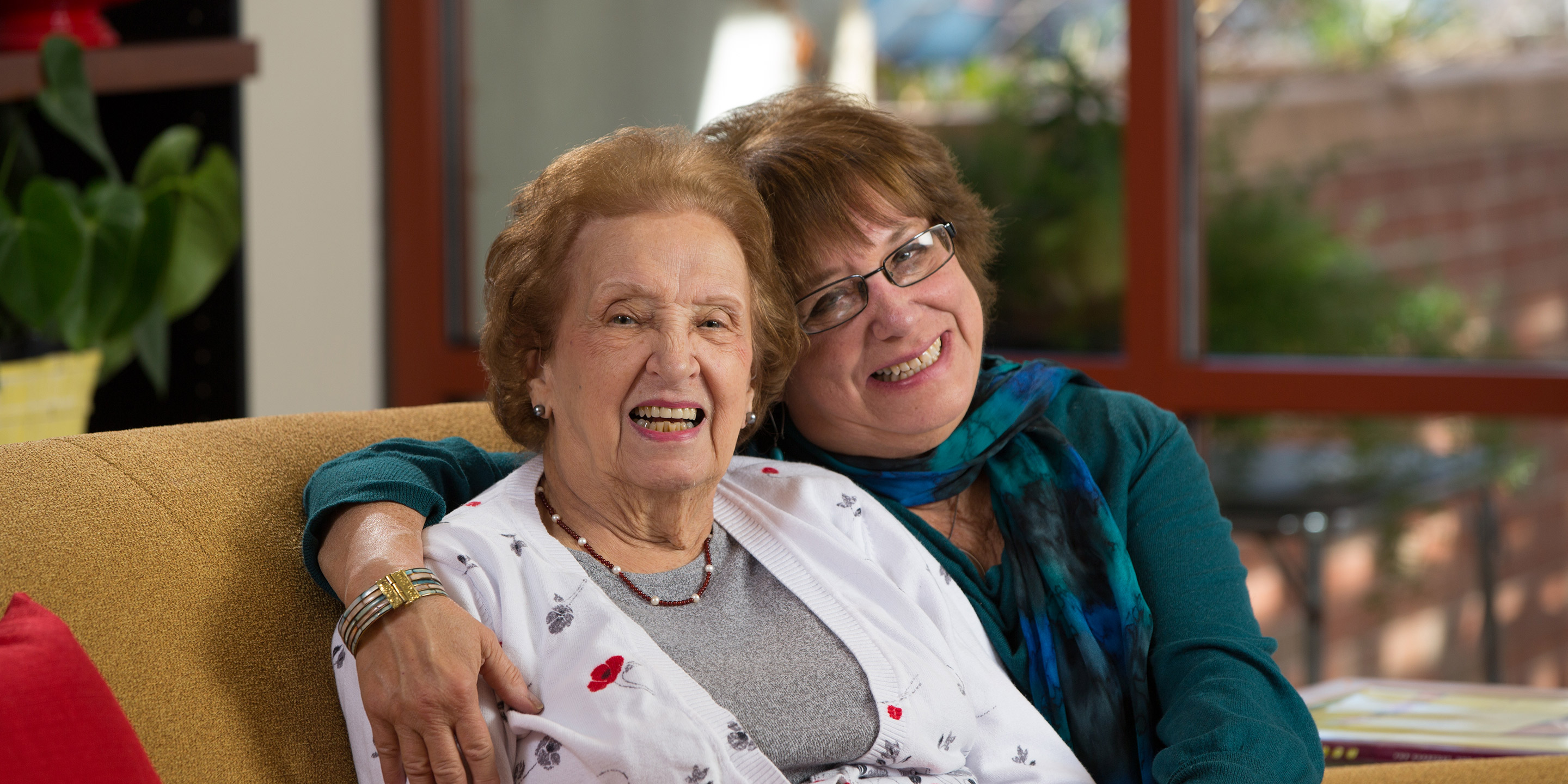 A daughter embraces her mother in a hug while both of them smile