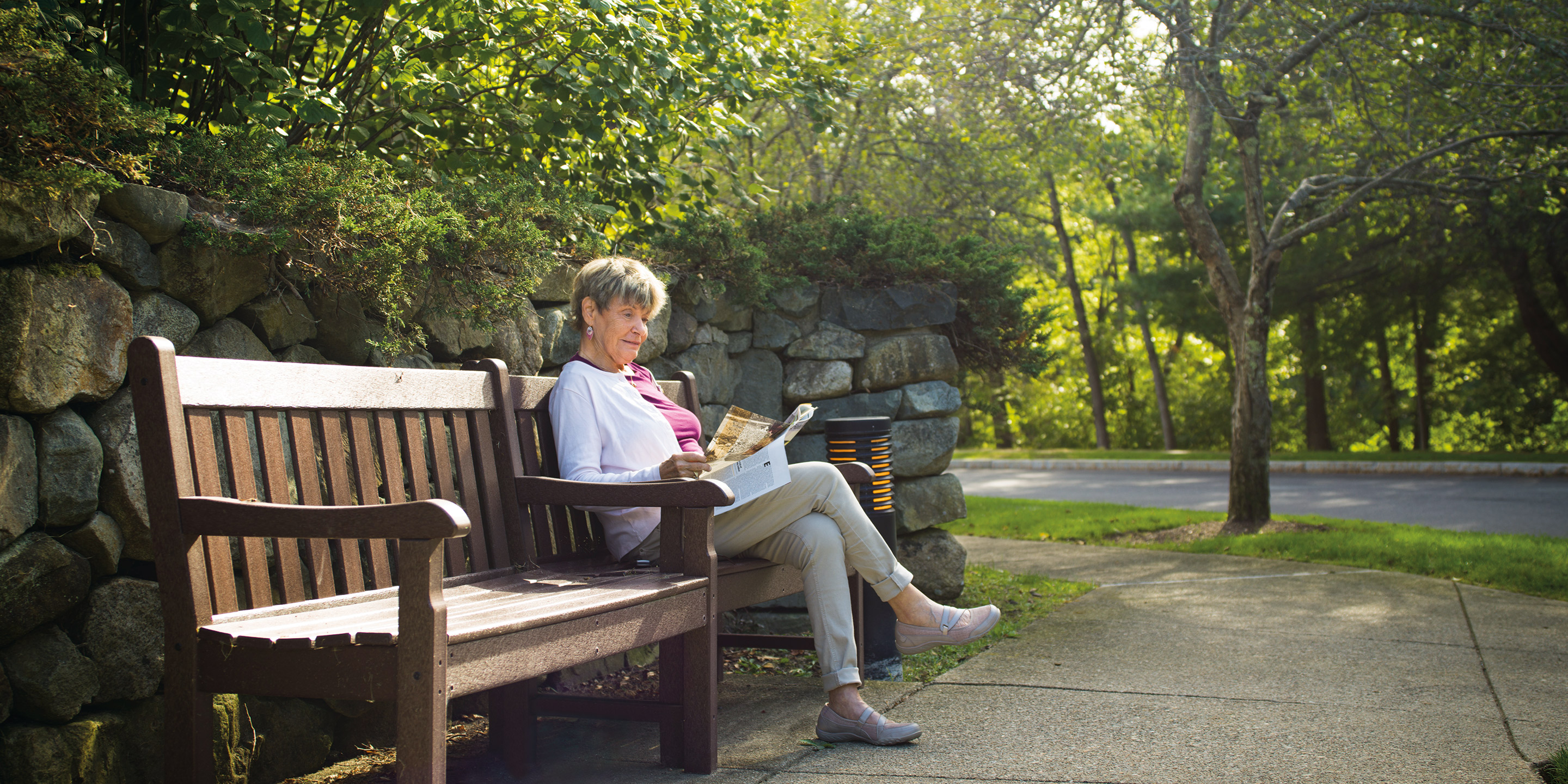 A female sits on a bench outside and reads