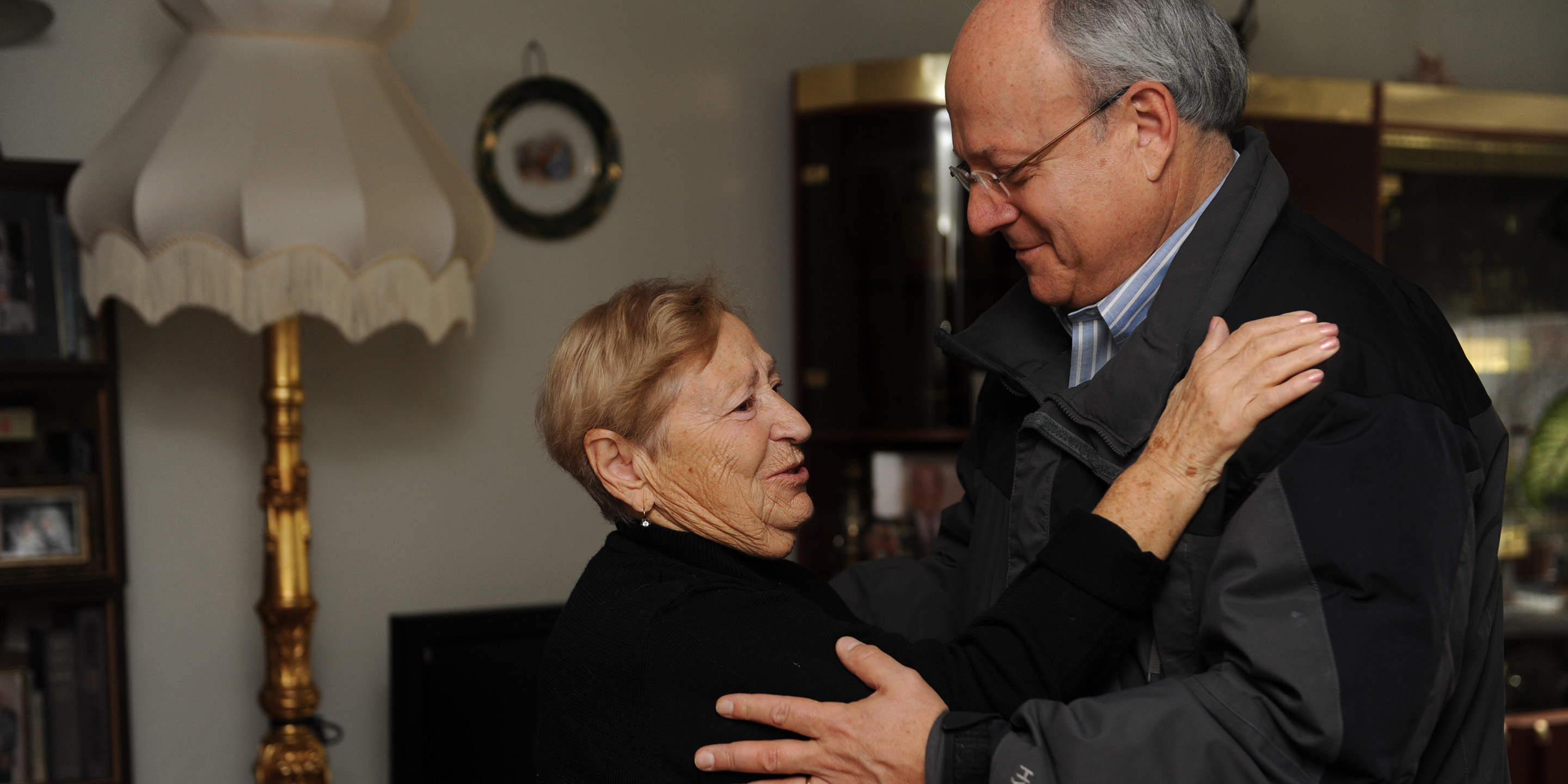 Hebrew SeniorLife's CEO Lou Woolf goes in for a hug with a female senior 