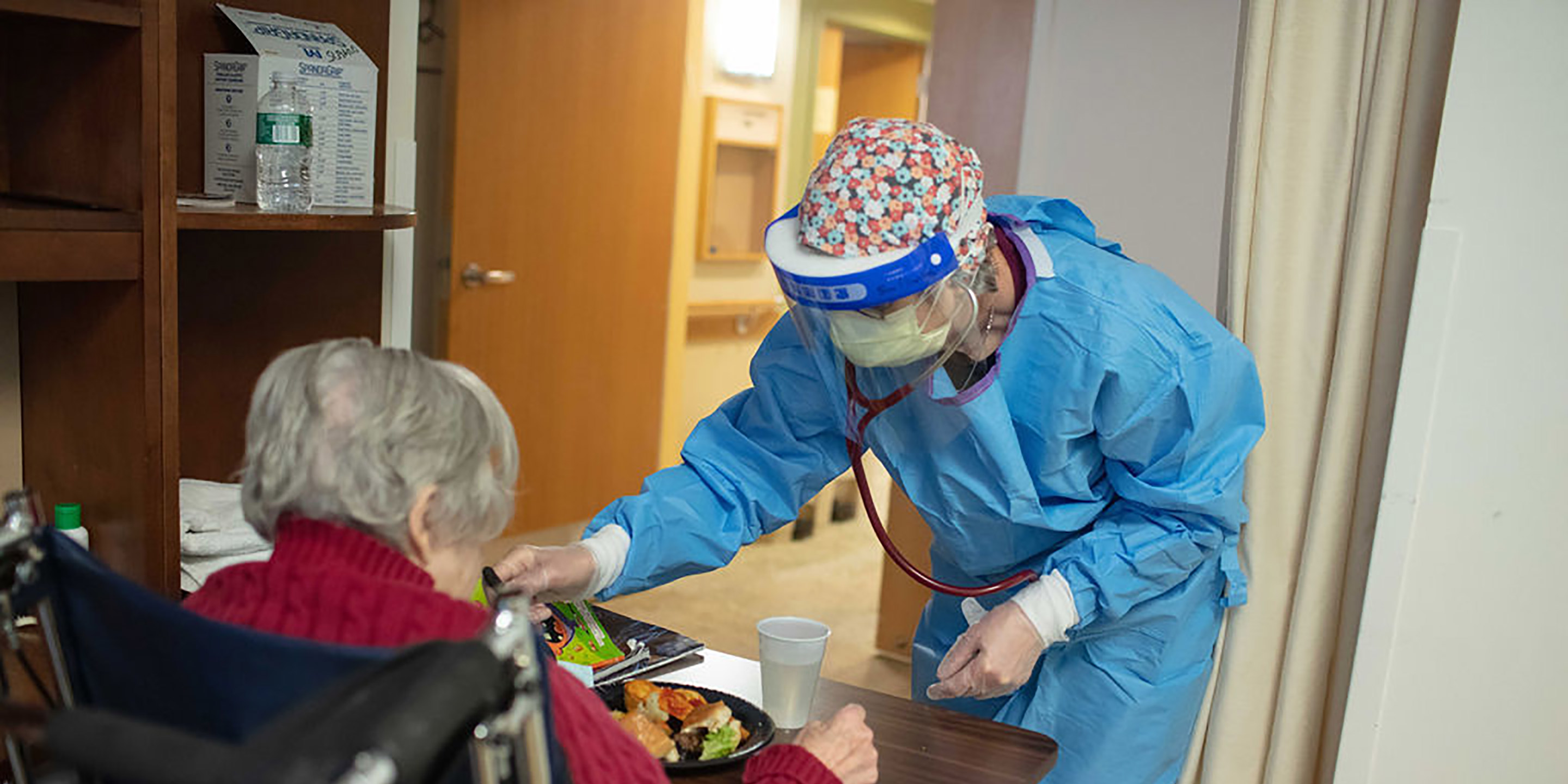 A NewBridge employee wears PPE while checking a resident's vitals.
