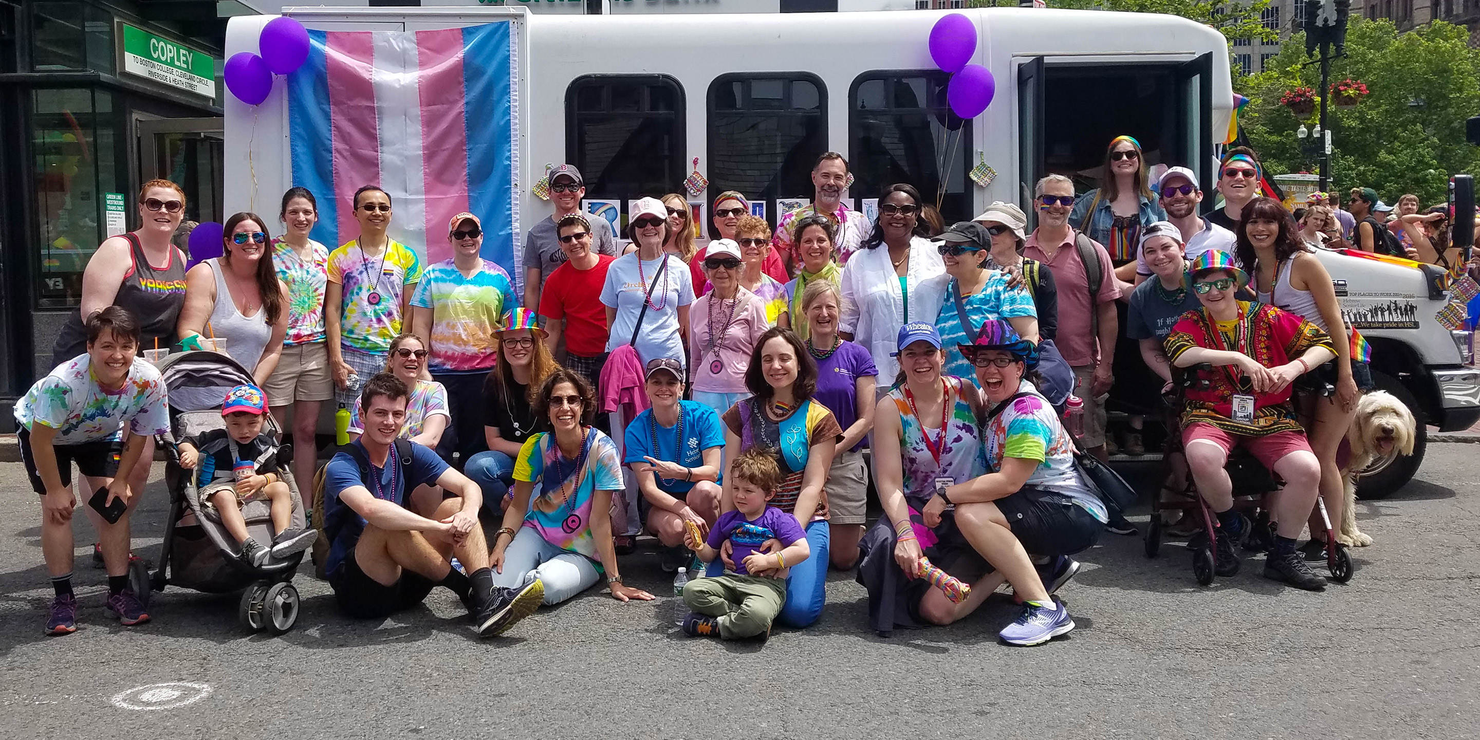 A group of HSL employees and residents stand in front of a bus at the Boston Pride Parade 