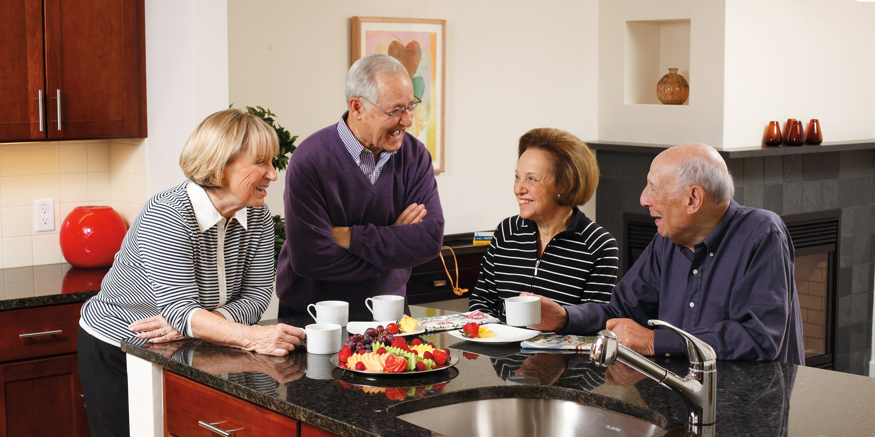 Four residents stand around a kitchen island and talk over coffee