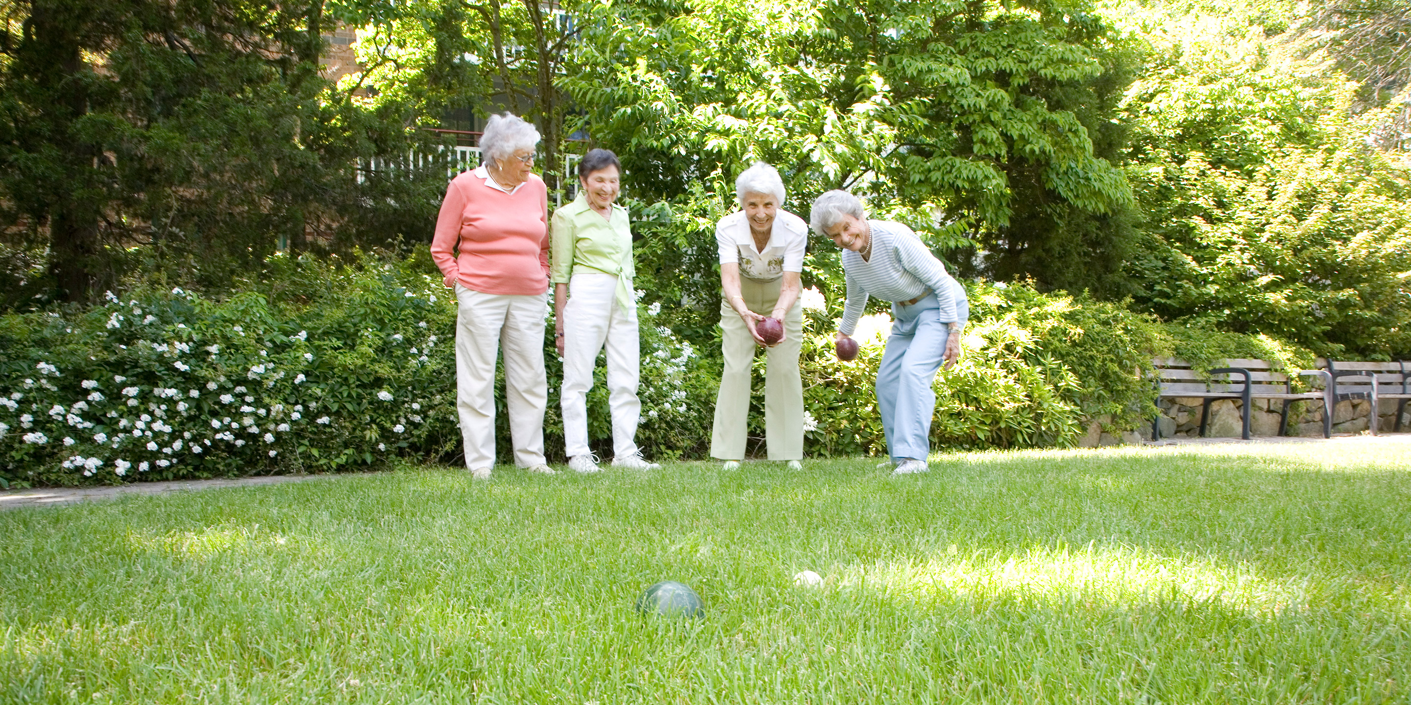 Four female residents play bocce ball outside