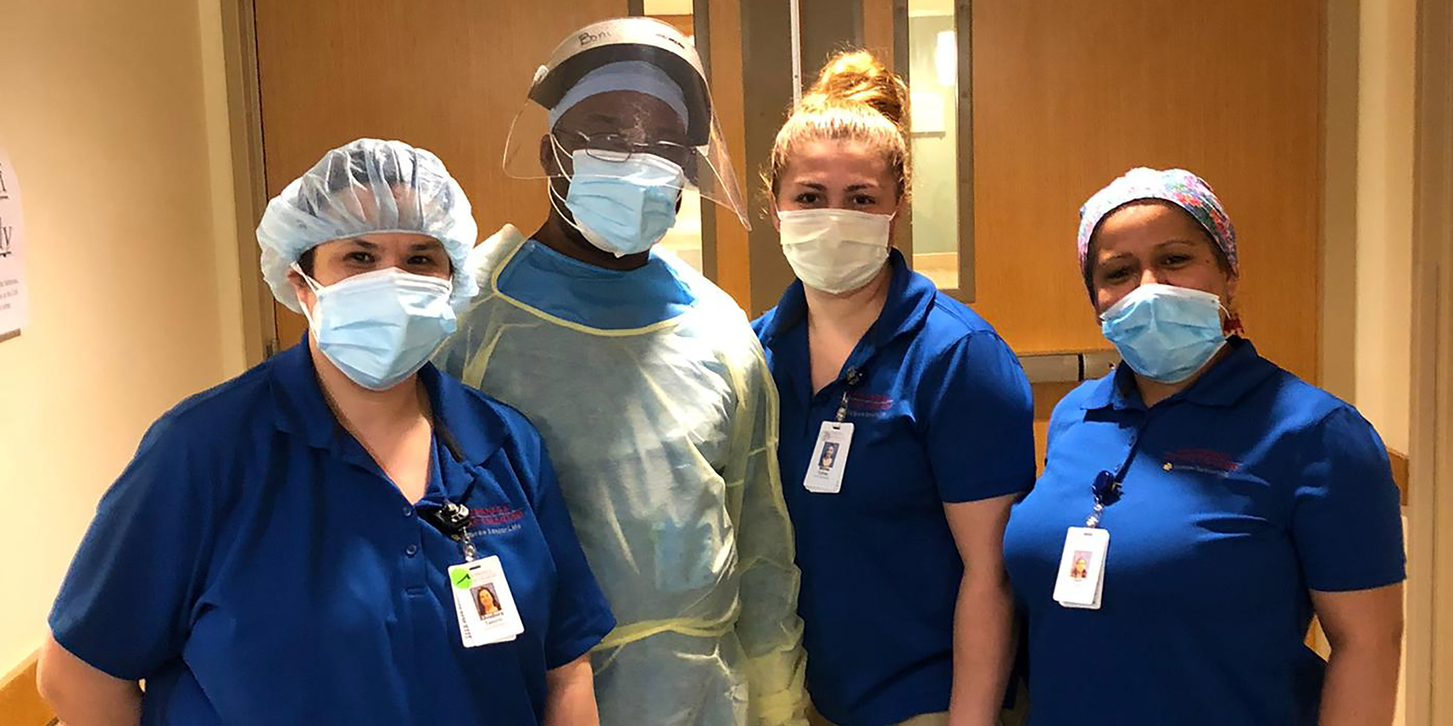 A group of Hebrew SeniorLife staff members stand together while wearing their PPE.