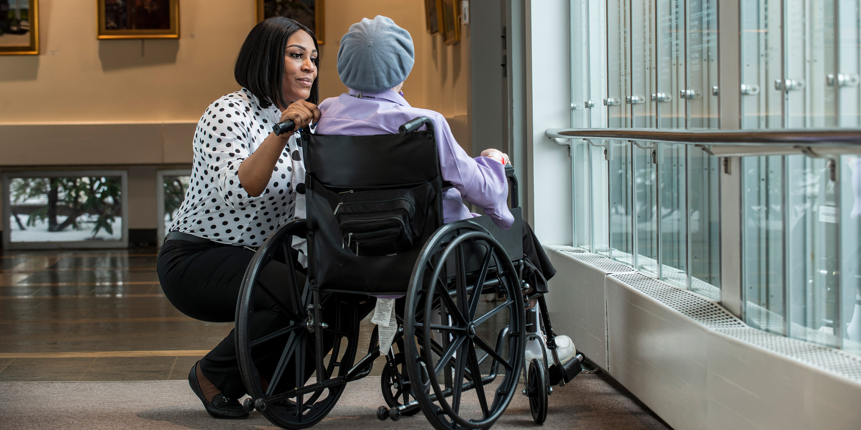 A HSL employee bends over to talk to a patient in a wheelchair. 