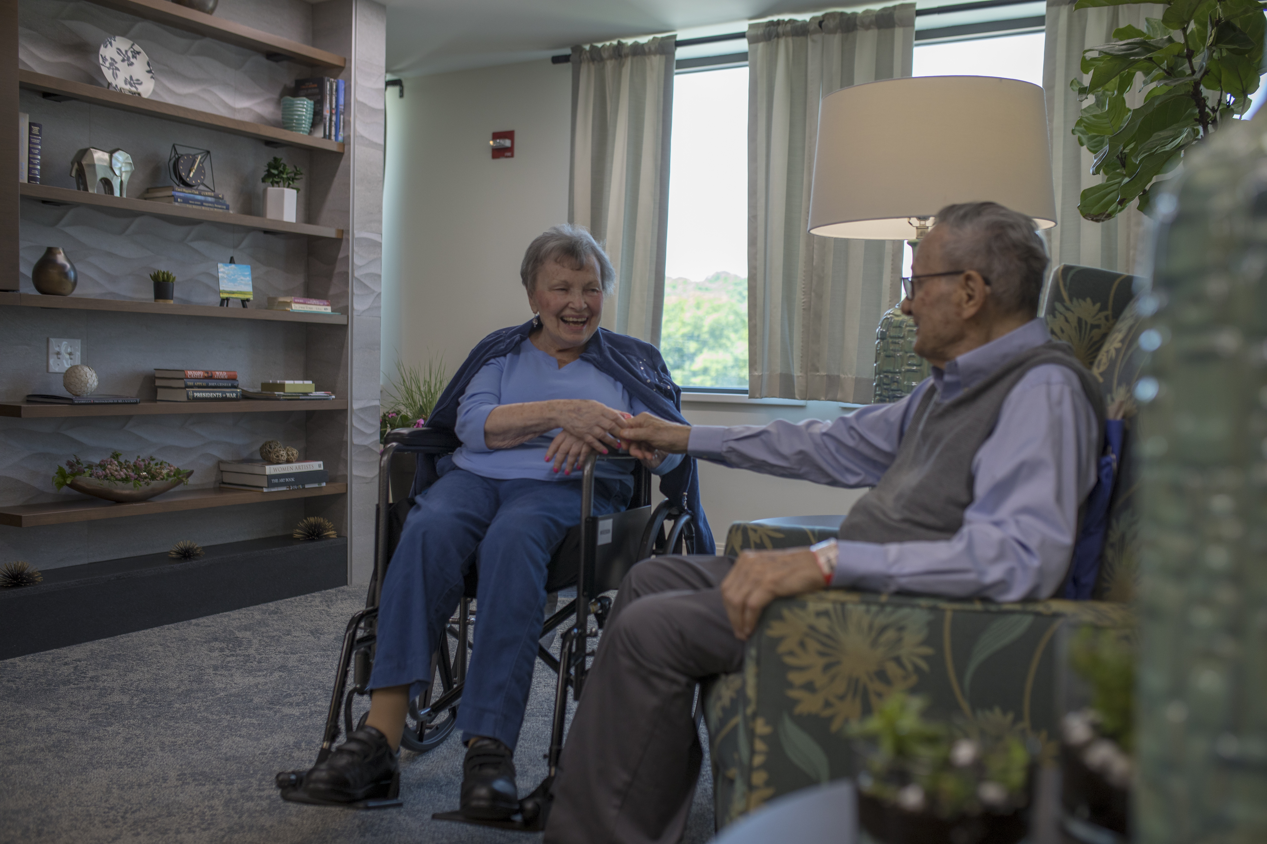 Older couple holding hands in residential facility.