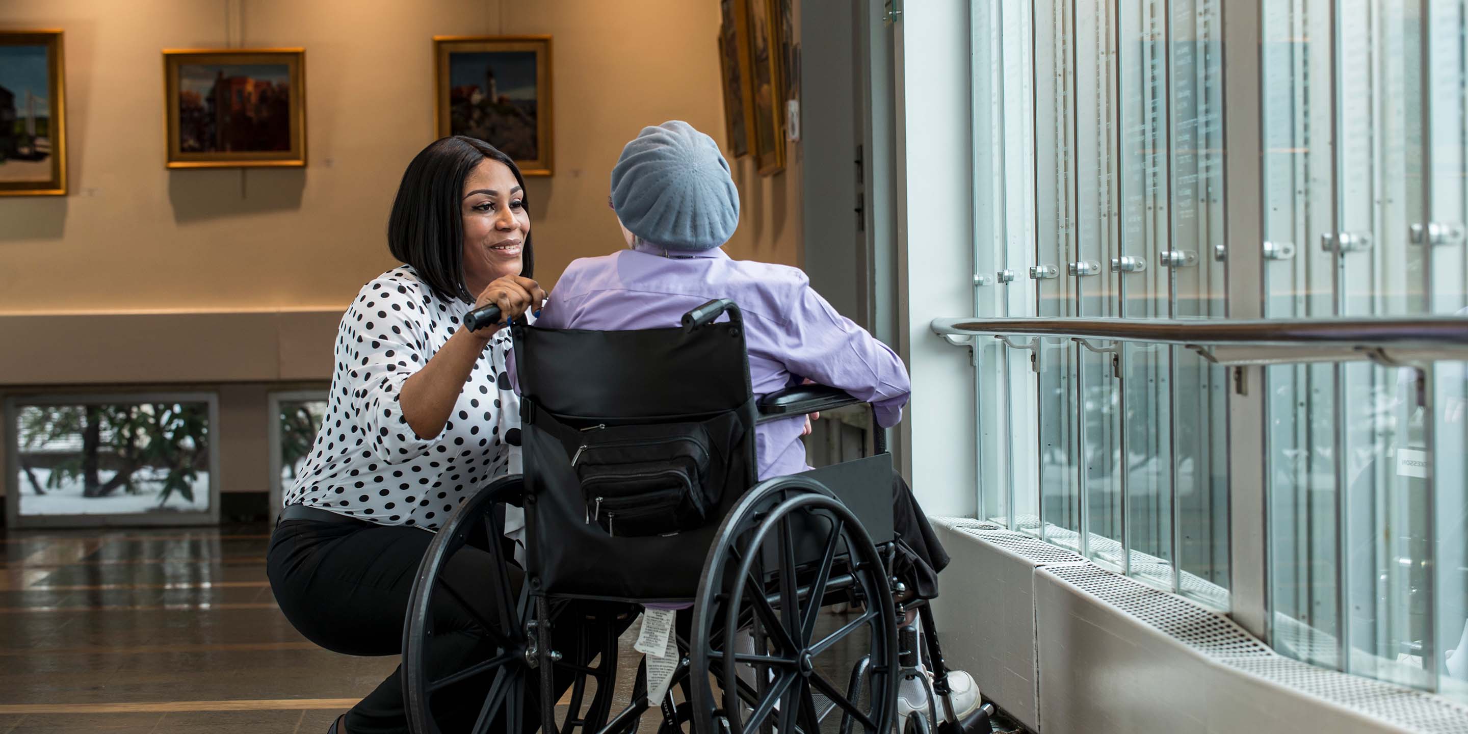 Woman kneels next to person in wheelchair.