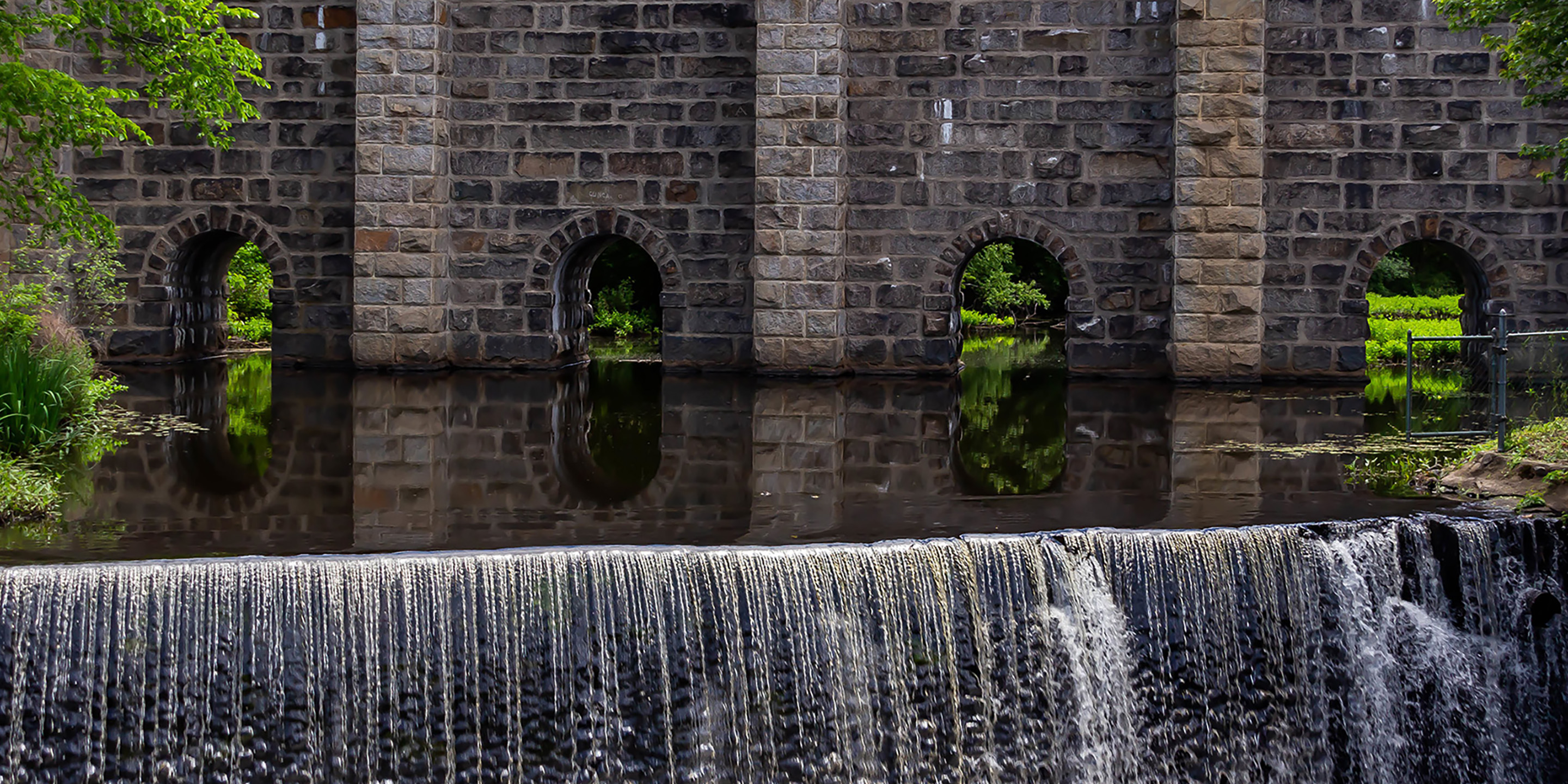 Water flowing through the Canton Viaduct, an arched stone railroad viaduct, and cascading down a spillover.