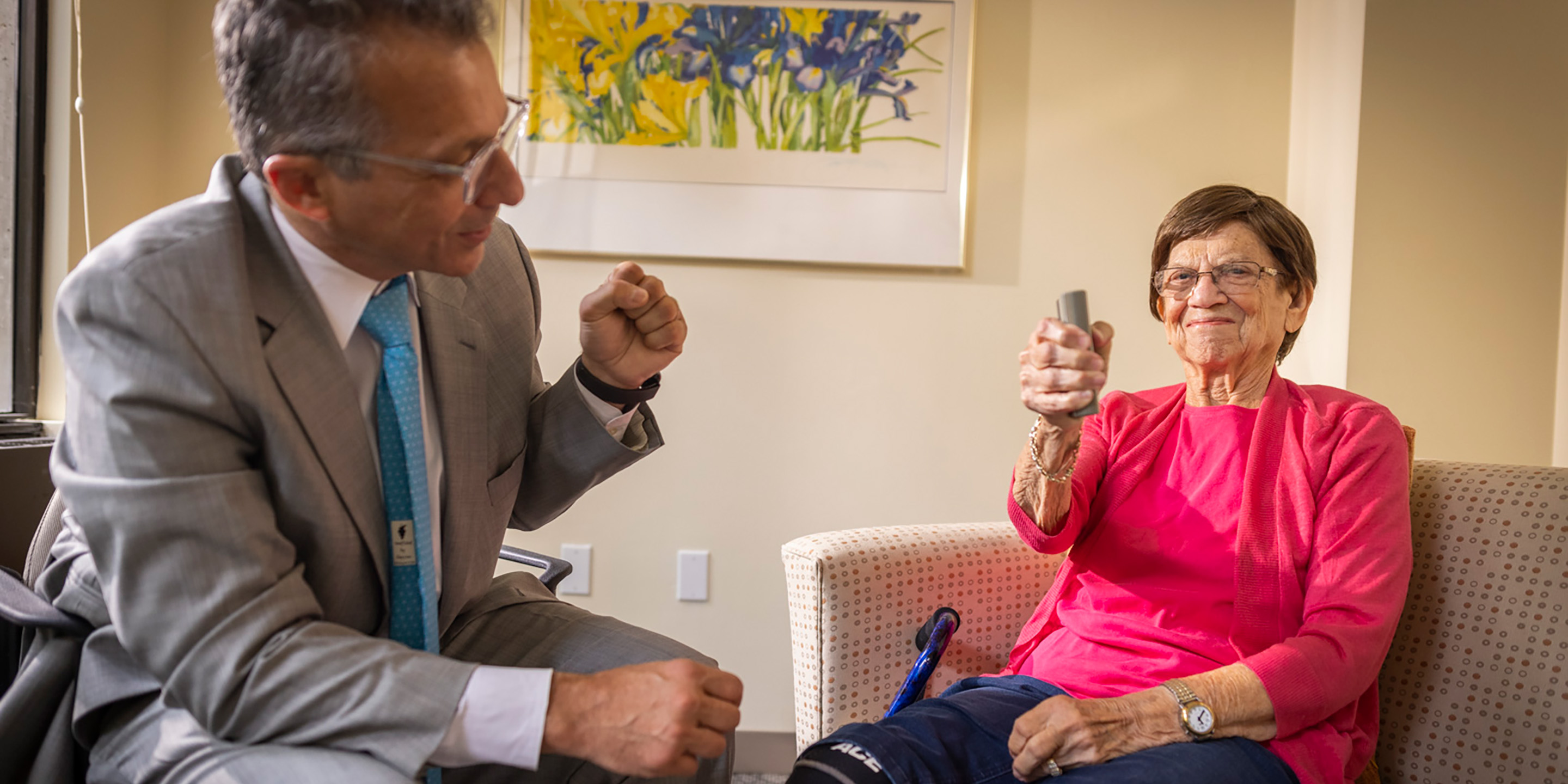 Doctor in grey suite with patient using a medical device.