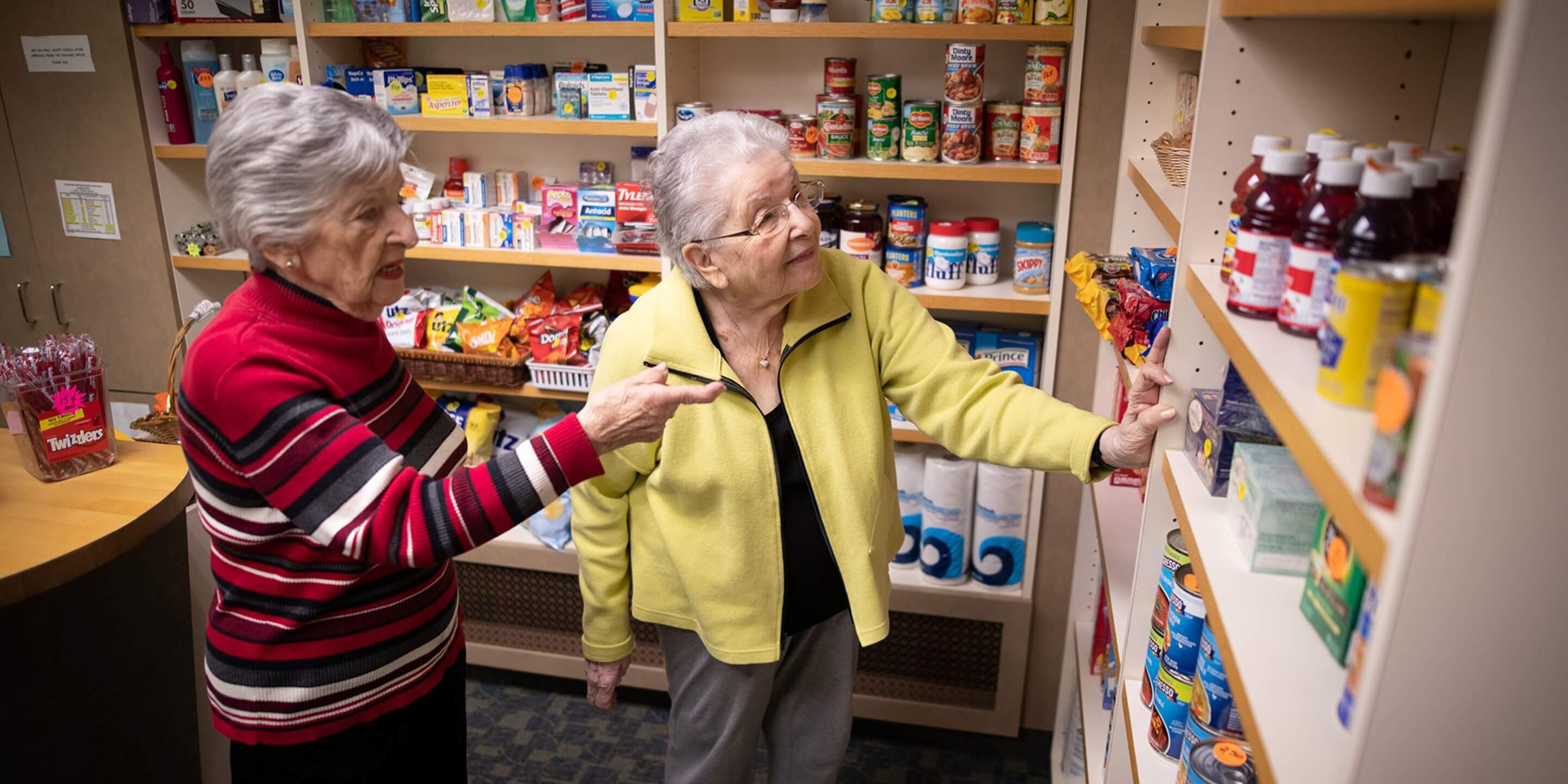 Two older women in a shop looking at items on shelves