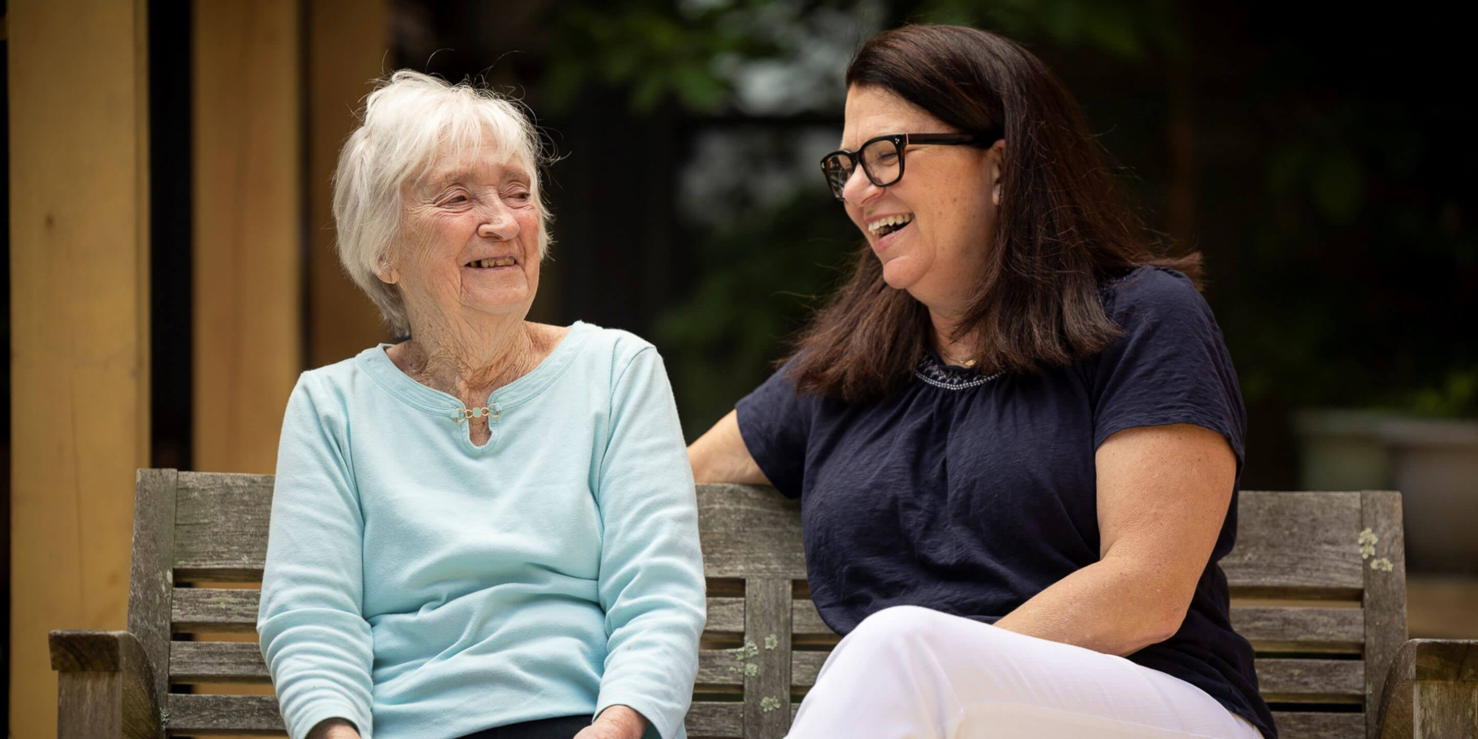 Older woman sitting on a bench with a younger woman.