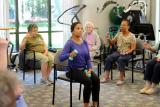 A female fitness instructor leads a group of seniors in a group fitness class involving weights. 