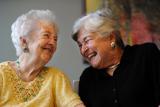 Two women hold hands while laughing about something 