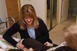 A Home Health worker helps a patient adjust her pant legs