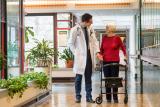 A male doctor at HRC stops and talks with a female patient as she walks with her walker.