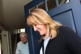 At the doorstep of his house, a nurse from Hebrew SeniorLife Home Health greets older man using a walker