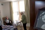 Hebrew SeniorLife's CEO Lou Woolf stands near a residents bed while talking to her and a female friend 