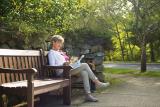 A female sits on a bench outside and reads