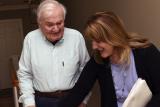 A Home Health worker smiles while helping a male patient with his walker 