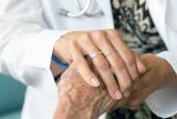 A female doctor wearing a white coat places her hand over a patient's hand 
