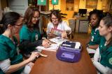 A group of nursing students sit around a table to learn from a Hebrew SeniorLife employee 