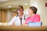 A Hebrew SeniorLife doctor puts her arm around a woman as she stands and talks with her 