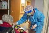 A NewBridge employee wears PPE while checking a resident's vitals.