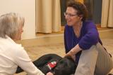 Rabbi Karen Landy and Tamari, her ministry service dog, sit on the floor with an elder woman
