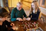 A male resident sits and puts together a puzzle with two young female volunteers