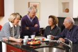 Four residents stand around a kitchen island and talk over coffee 