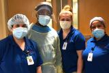 A group of Hebrew SeniorLife staff members stand together while wearing their PPE.