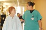 A patient smiles while walking down a hallway with a staff member at HRC Roslindale.