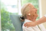 A female resident looks up and smiles as someone pats her shoulder 