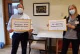 HSL employees Matt Hollingshead and Kim Brooks hold up signs saying why they received their COVID-19 vaccines.