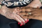 A younger woman reassures an older woman by putting her hand over the older woman’s clasped hands.