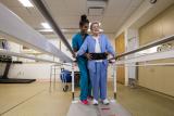 young nurse guiding an elderly patient to walk with guiderail assistance during physical rehabilitation 