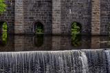 Water flowing through the Canton Viaduct, an arched stone railroad viaduct, and cascading down a spillover.