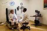 Doctor sitting on stool speaks with elderly patient in an examining room